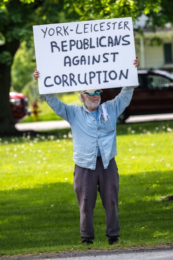 Man holding anti-corruption Republican protest sign outdoors