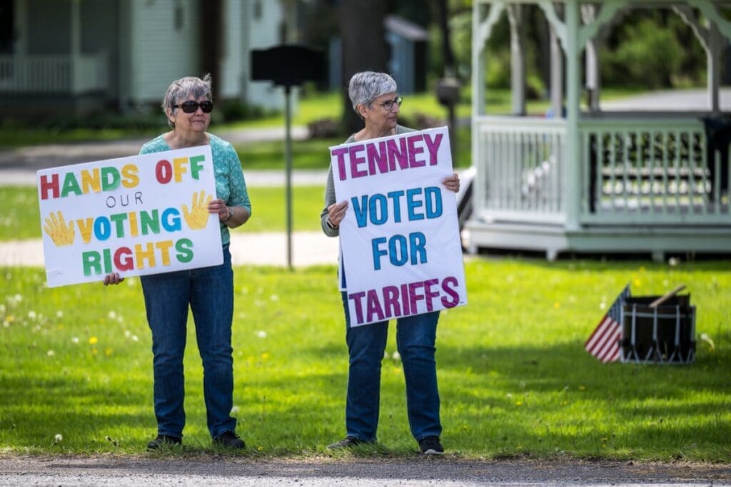 Two women holding voting rights protest signs outdoors