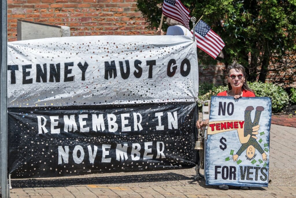 Protester holds signs opposing Tenney with American flags