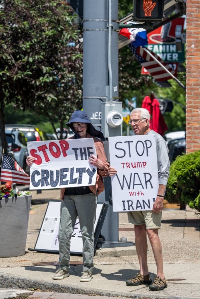 Two protesters holding anti-war and anti-cruelty signs on street