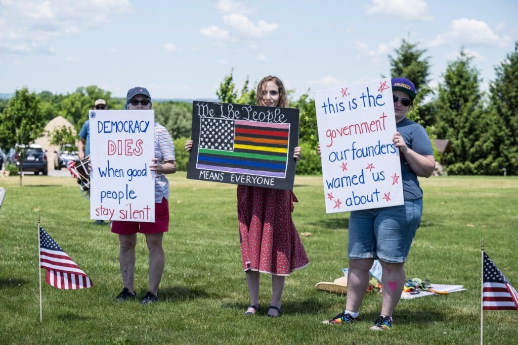 Protesters holding democracy and equality signs at outdoor rally